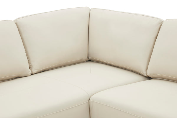 Vista cercana de sofá chaise de color beige sobre un fondo blanco. 