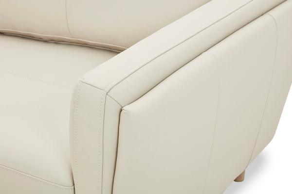 Primer plano de un sofá chaise beige con detalles de costura visibles.