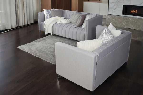 Sofá y loveseat gris con cojines en un salón con chimenea.