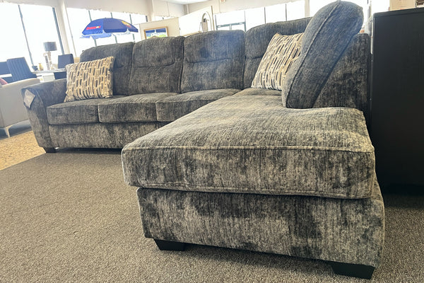 Sofá modular gris en una habitación con suelo alfombrado en una sala de exposición