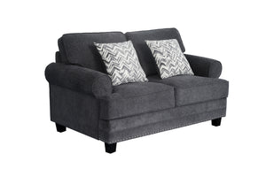 Loveseat tapizado en tela gris oscuro con brazos redondeados, cojines decorativos con patrón en zigzag gris y blanco, detalles de tachuelas metálicas en la base y patas negras de madera.