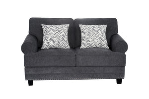 Loveseat tapizado en tela gris oscuro con brazos redondeados, cojines decorativos con patrón en zigzag gris y blanco, detalles de tachuelas metálicas en la base y patas negras de madera.