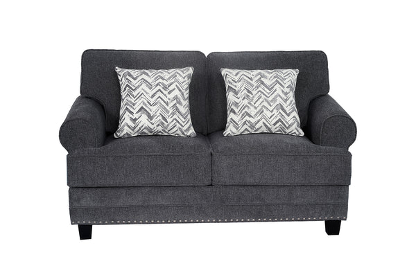 Loveseat tapizado en tela gris oscuro con brazos redondeados, cojines decorativos con patrón en zigzag gris y blanco, detalles de tachuelas metálicas en la base y patas negras de madera.