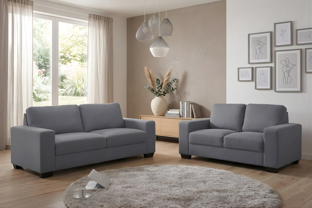 Conjunto de sofás grises en una sala de estar con elementos decorativos.