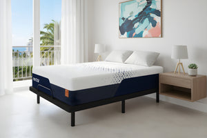 Cama con mattress en dormitorio luminoso con grandes ventanales y cuadro en la pared.