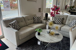 Sofá y loveseat modular beige con cojines estampados en una sala de exposición.