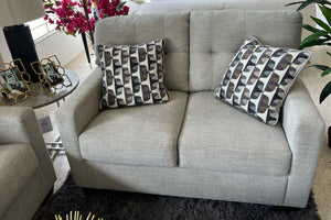 Loveseat beige con cojines estampados en una sala de exposición.