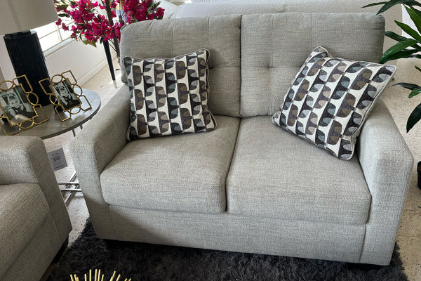 Loveseat beige con cojines estampados en una sala de exposición.