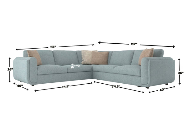 Sofá seccional esquinero en color azul claro con cojines decorativos beige. La imagen muestra dimensiones del mueble: 115 pulgadas por cada lado, 40 pulgadas de profundidad y 26 pulgadas de altura en los brazos.