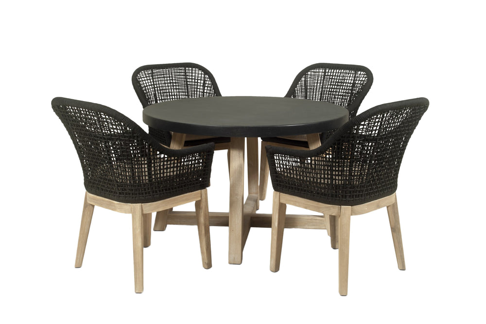 Mesa redonda con cuatro sillas de mimbre verde oscuro sobre fondo blanco. 