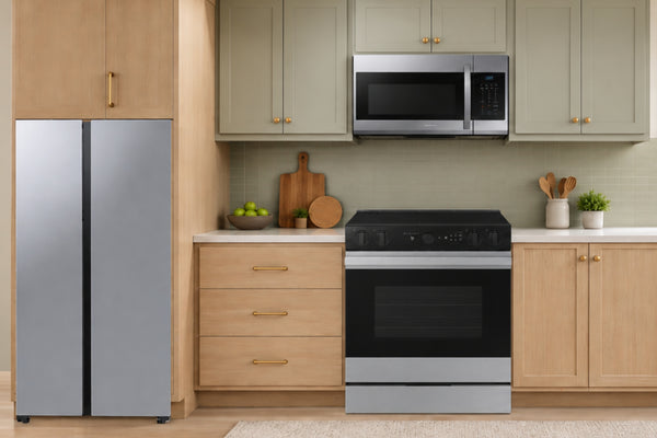 Juego de enseres Samsung de tres piezas en cocina moderna: nevera side-by-side plateada, microondas sobre la estufa eléctrica con horno y gabinetes de madera.