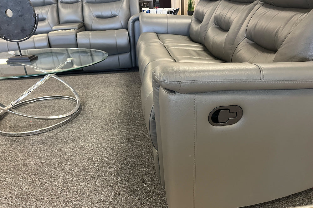 Sofá reclinable de gris oscuro en una sala moderna con objetos decorativos y una ventana en el fondo. 