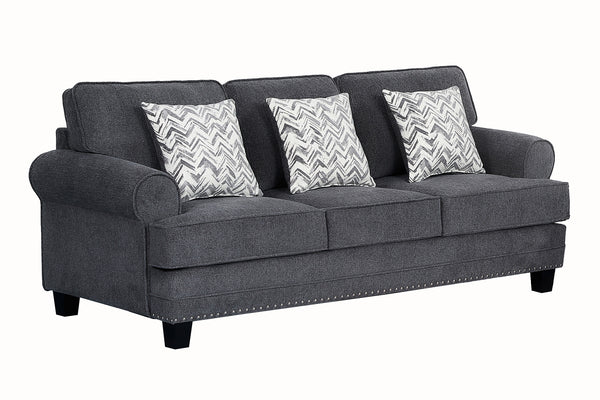 Sofá tapizado en tela gris oscuro con brazos redondeados, cojines decorativos con patrón en zigzag gris y blanco, detalles de tachuelas metálicas en la base y patas negras de madera.