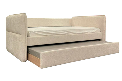Cama tipo daybed tapizada en tela color beige con respaldo y brazos laterales acolchados. Incluye una cama nido inferior extraíble con mattress, ideal para maximizar espacio y ofrecer una solución versátil para dormir.
