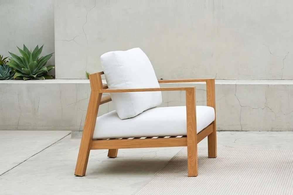 Sillón de madera con cojines blancos.