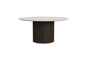 Una moderna mesa de centro redonda con tablero de mármol claro y base de pedestal estriada de color marrón oscuro, mostrada sobre un fondo blanco liso.