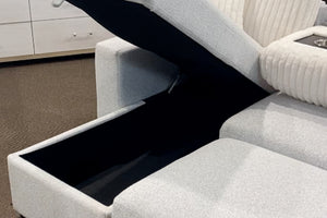 Sofá modular contemporáneo tapizado en tela blanca texturizada con compartimento de almacenamiento oculto bajo el asiento elevable, cojines acanalados en color crema y consola central con portavasos integrados.