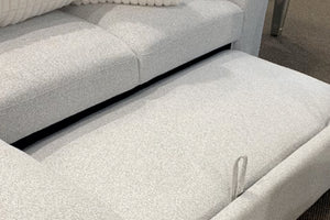Sofá modular contemporáneo tapizado en tela blanca texturizada con base extensible tipo chaise longue, mostrando un asiento deslizante acolchado y cojines decorativos acanalados en color crema.