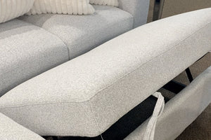 Sofá modular contemporáneo tapizado en tela blanca texturizada con respaldo reclinable ajustable, mostrando el mecanismo elevable del cojín trasero y cojines decorativos acanalados en color crema.