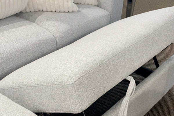 Sofá modular contemporáneo tapizado en tela blanca texturizada con respaldo reclinable ajustable, mostrando el mecanismo elevable del cojín trasero y cojines decorativos acanalados en color crema.