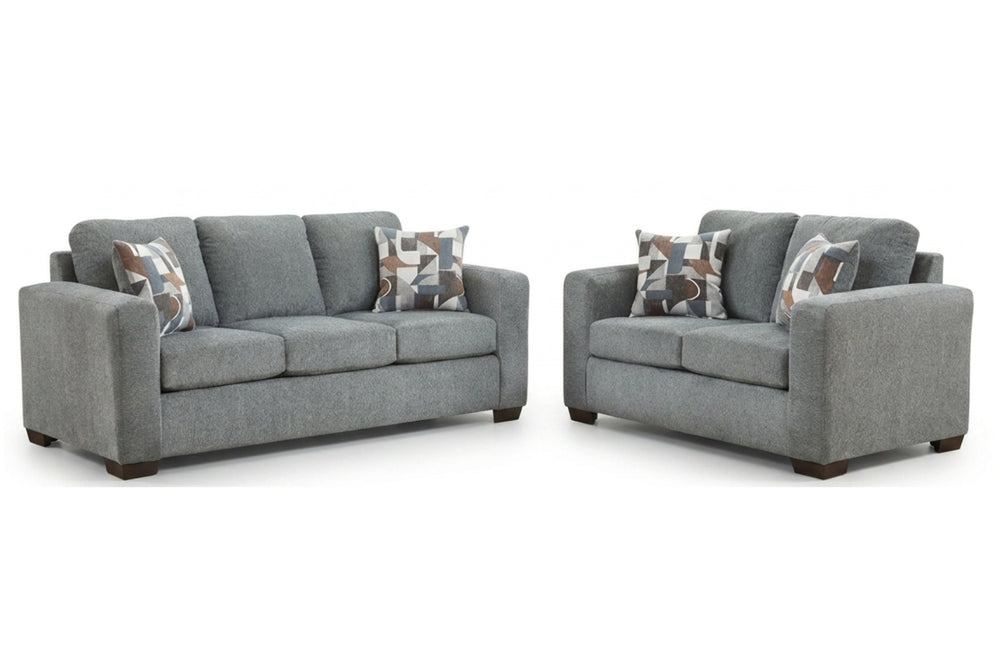 Sofá y loveseat grises con cojines estampados sobre un fondo blanco.