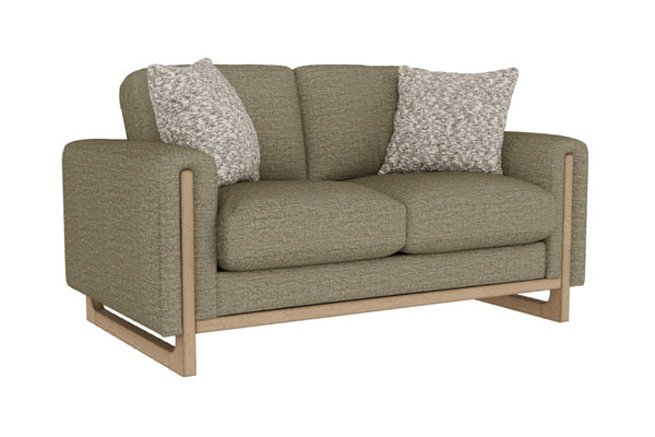 Loveseat de color verde claro con cojines decorativos sobre un fondo blanco. 