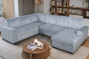 Seccional gris en una sala de estar con una mesa de centro de madera y una estantería.