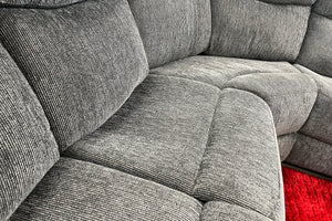 Sofá modular gris en un entorno de exposición con una alfombra roja. 