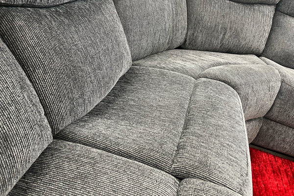 Sofá modular gris en un entorno de exposición con una alfombra roja. 