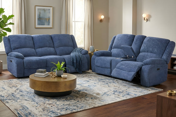 Conjunto de sofá y loveseat reclinable azul en una sala de estar con una mesa de centro con el tope color dorado y la base color negro  y objetos decorativos.
