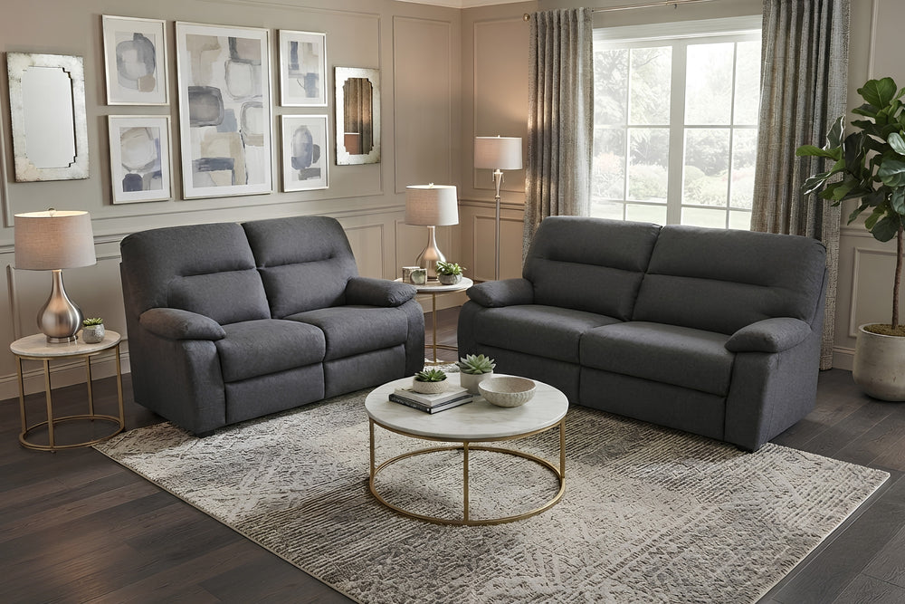 Un sofá biplaza reclinable de tela gris oscuro y un loveseat reclinable a juego, mostrados sobre un fondo blanco liso.