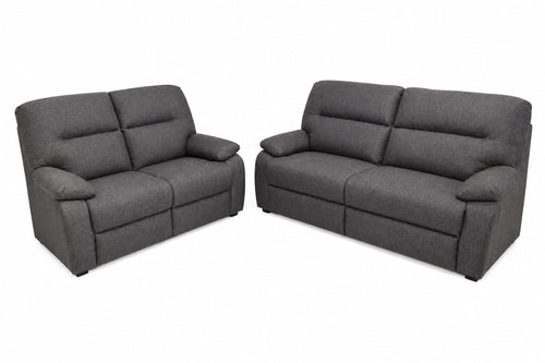 Un sofá biplaza reclinable de tela gris oscuro y un loveseat reclinable a juego, mostrados sobre un fondo blanco liso.