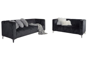 Sofá y loveseat de terciopelo gris oscuro con cojines decorativos sobre un fondo blanco.