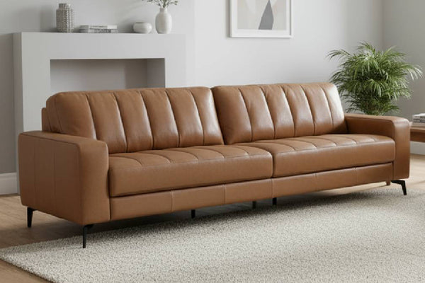 Sofá de cuero 100% marrón en una sala de estar con chimenea y plantas.