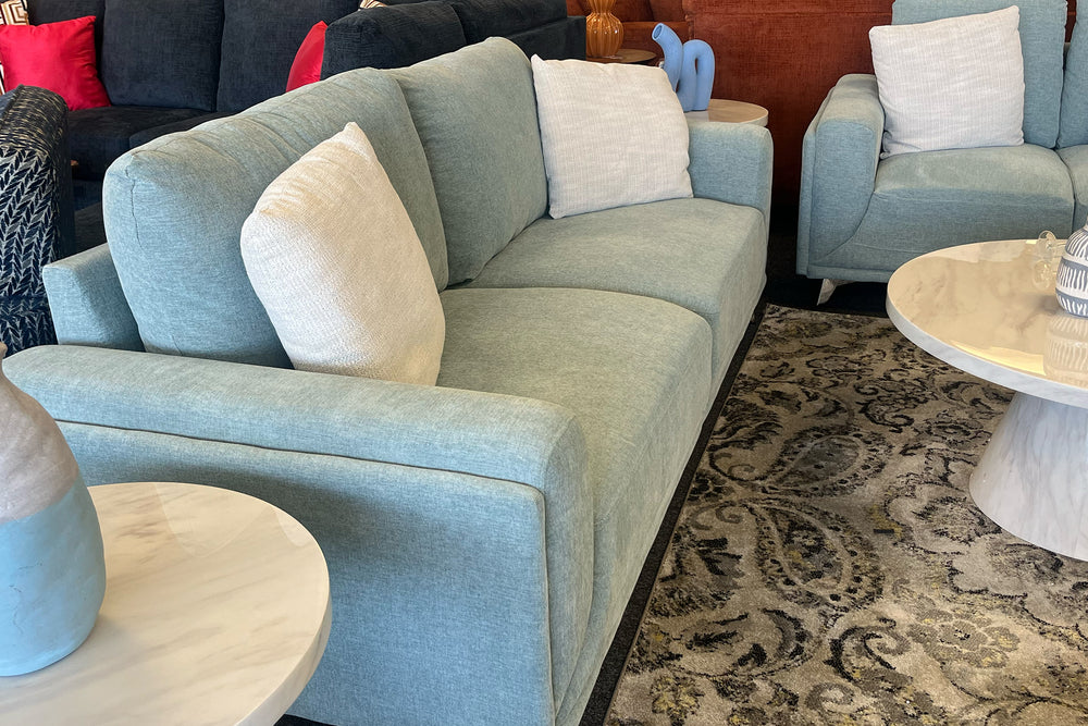 Loveseat verde con dos cojines sobre fondo blanco.