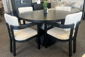 Mesa redonda de comedor hecha de madera negra con base cilíndrica y con cuatro sillas. 