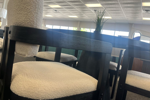 Vista cercana de silla hecha de madera negra con respaldo y asiento blanco suave y brazos. 