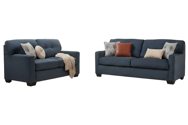 Sofá y loveseat de color azul oscuro con cojines sobre un fondo blanco. 