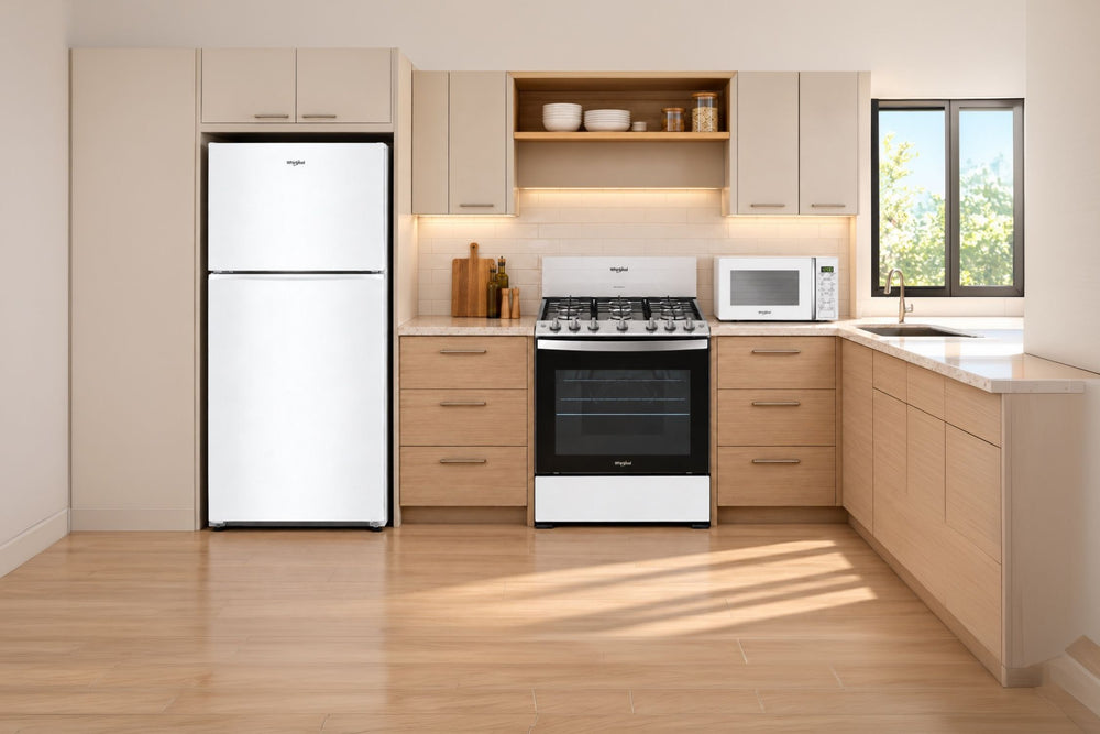 Una escena de cocina moderna que presenta una estufa de gas en blanco y negro, una nevera blanca y un microondas blanco, ubicada contra gabinetes de madera clara y azulejos.