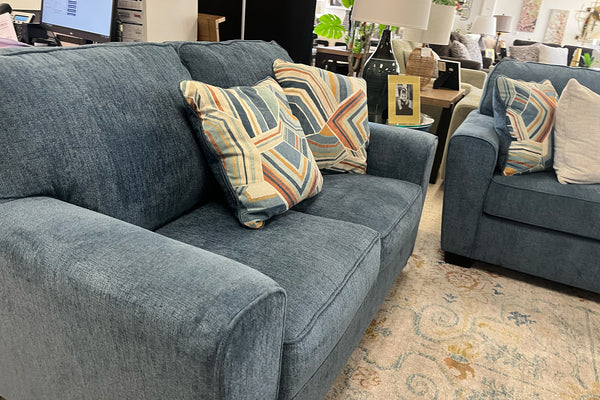 Sofá gris con cojines estampados en un ambiente de sala de estar.