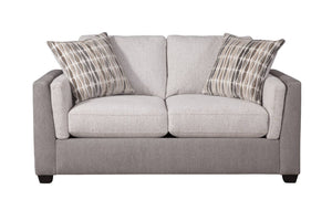 Loveseat de dos plazas tapizado en tela color beige claro, con cojines de asiento y respaldo acolchados y apoyabrazos redondeados. Incluye dos cojines decorativos con patrón en tonos neutros. El sofá presenta patas bajas oscuras y diseño contemporáneo, mostrado sobre fondo blanco.