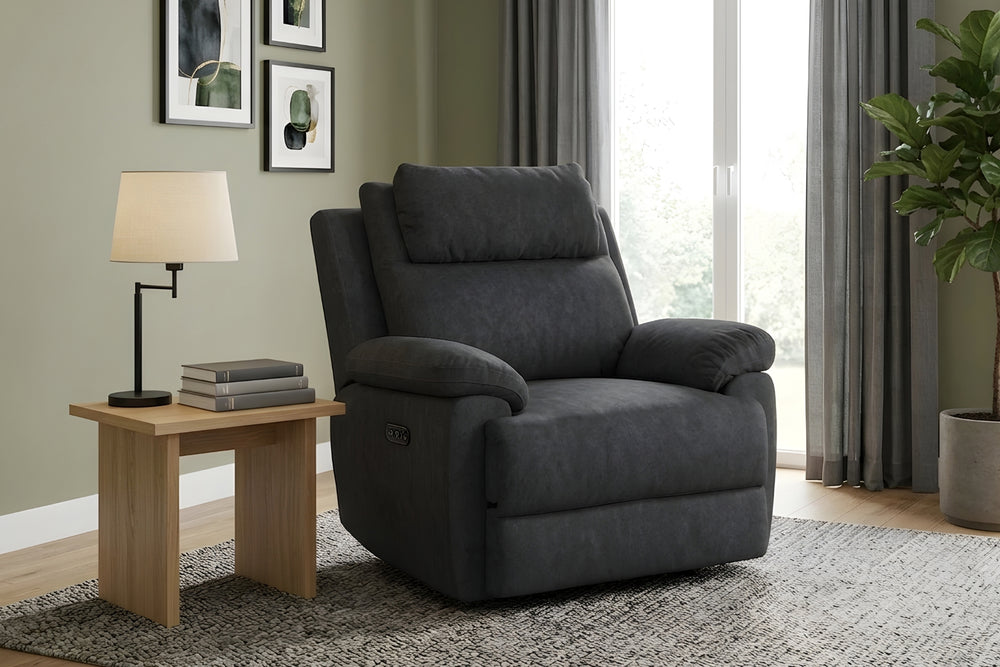 Butaca reclinable gris oscuro tapizada en tela, con respaldo alto acolchado, reposacabezas ajustable, brazos anchos tipo almohada, asiento amplio y panel de controles lateral, sobre un fondo blanco. 