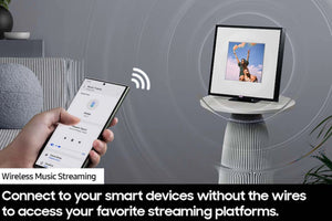 Mano sosteniendo un teléfono inteligente con una aplicación de transmisión de música y una pantalla que muestra un dispositivo que reproduce música.