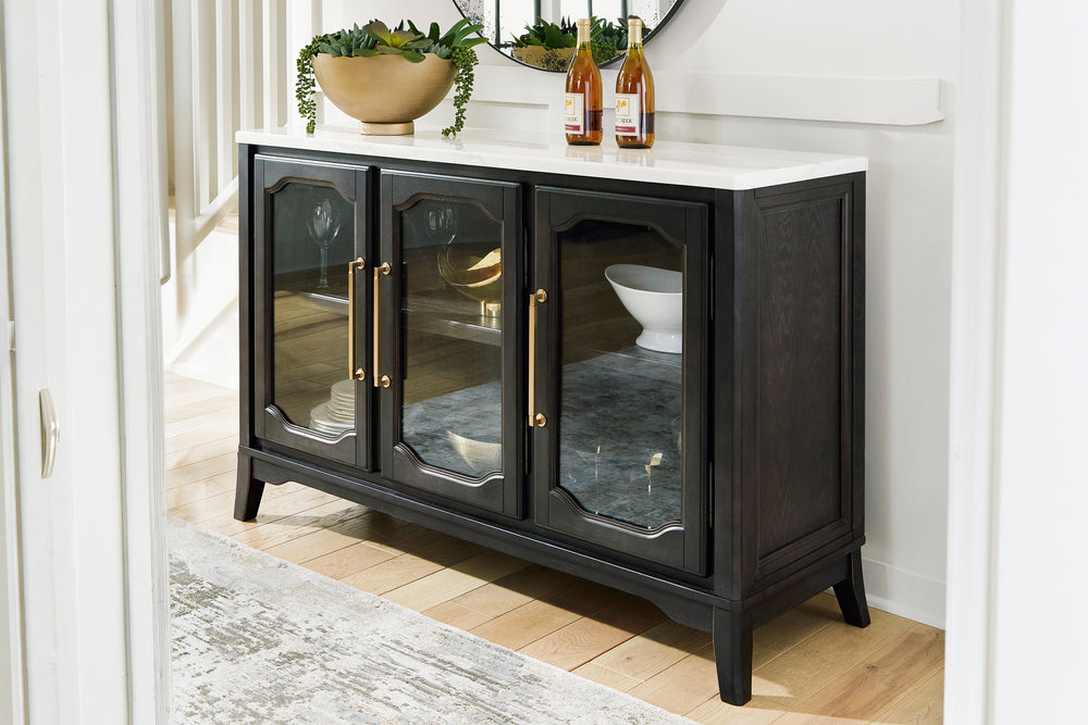 Un servidor de madera negra con superficie blanca, que cuenta con tres puertas con frente de vidrio, tiradores dorados y paneles decorativos, mostrado sobre un fondo blanco.