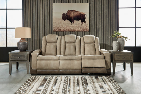 Sofá reclinable beige en una sala de estar con un gran cuadro de un bisonte en la pared.