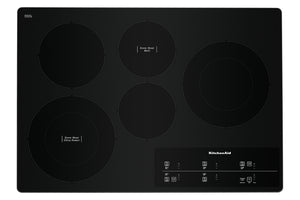 Un tope empotrable de vitrocerámica negra con cuatro elementos calefactores circulares y un panel de control táctil en la esquina inferior derecha, que luce el logotipo de KitchenAid.