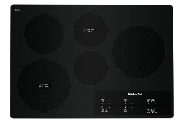Un tope empotrable de vitrocerámica negra con cuatro elementos calefactores circulares y un panel de control táctil en la esquina inferior derecha, que luce el logotipo de KitchenAid.