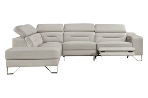 Un sofá modular de color beige claro con una chaise longue a la izquierda y un reposapiés reclinable extendido a la derecha, sostenido por finas patas de metal plateado, que se muestra sobre un fondo blanco liso.