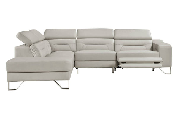 Un sofá modular de color beige claro con una chaise longue a la izquierda y un reposapiés reclinable extendido a la derecha, sostenido por finas patas de metal plateado, que se muestra sobre un fondo blanco liso.