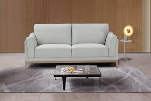 Sofá gris claro en ambiente de sala de estar con mesa de centro y elementos decorativos.